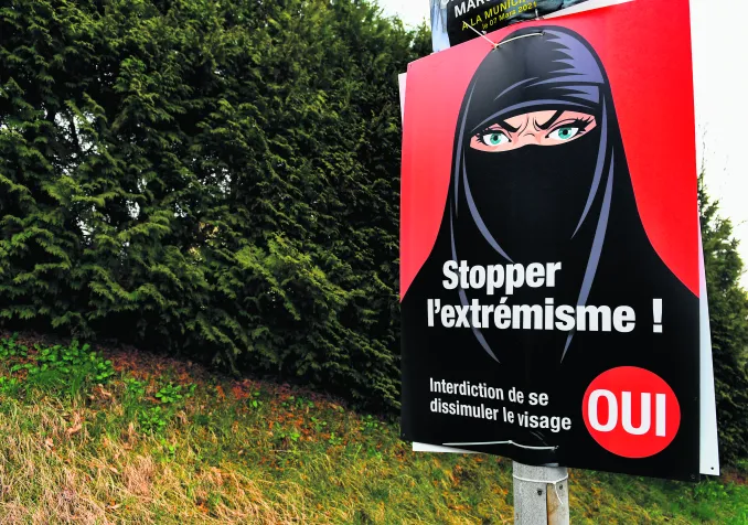 Vevey, le 7 mars 2021. Une affiche en faveur de l’interdiction de se dissimuler le visage acceptée par les électeurs suisses ce jour-là. Si le type de vêtements représentés est ultraminoritaire en Suisse, les promoteurs de l’initiative ont largement utilisé cette symbolique dans leur campagne. © Shutterstock