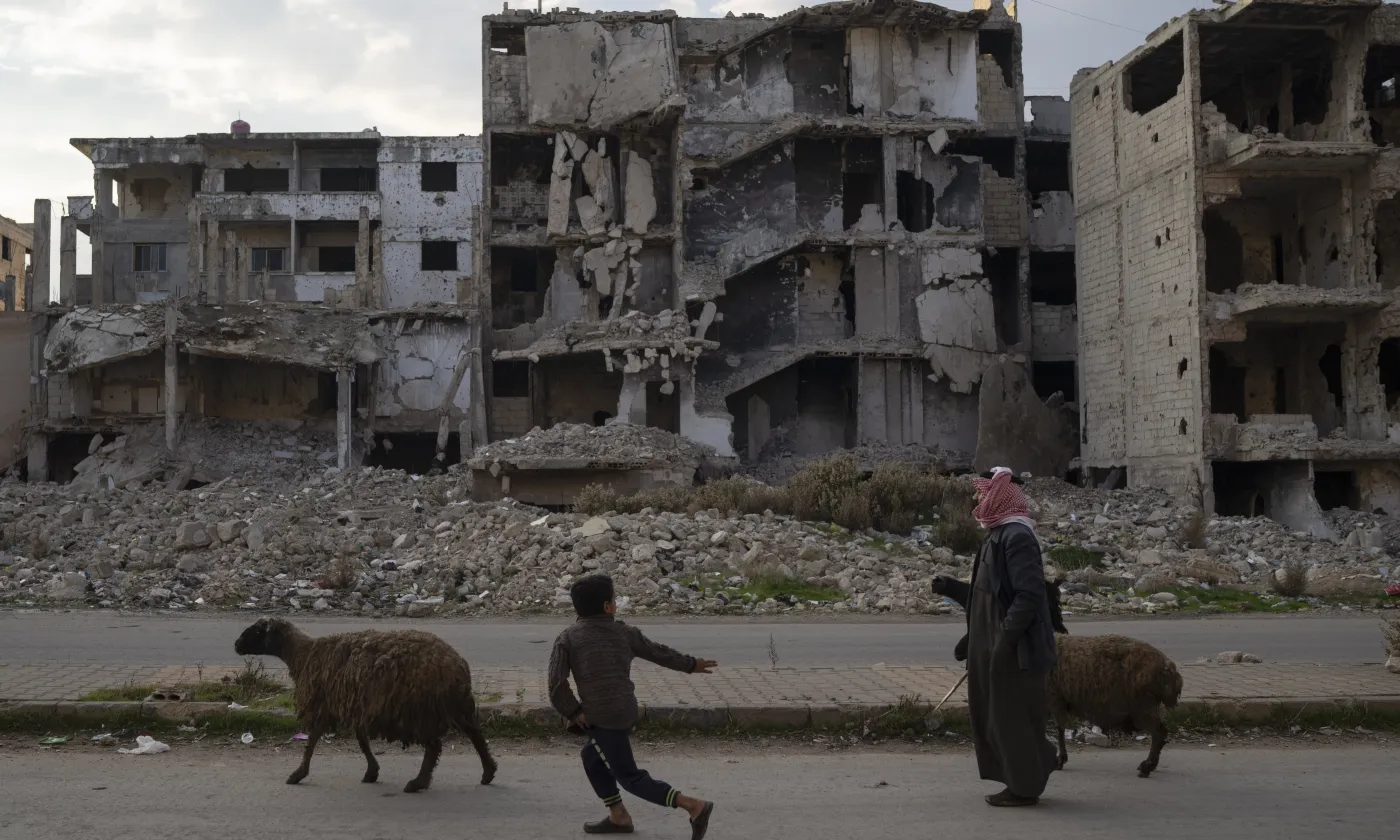Un enfant court après les moutons en passant devant des bâtiments détruits pendant la guerre civile dans le quartier de Khalidiya à Homs, en Syrie, mercredi 1er janvier 2025.  Keystone