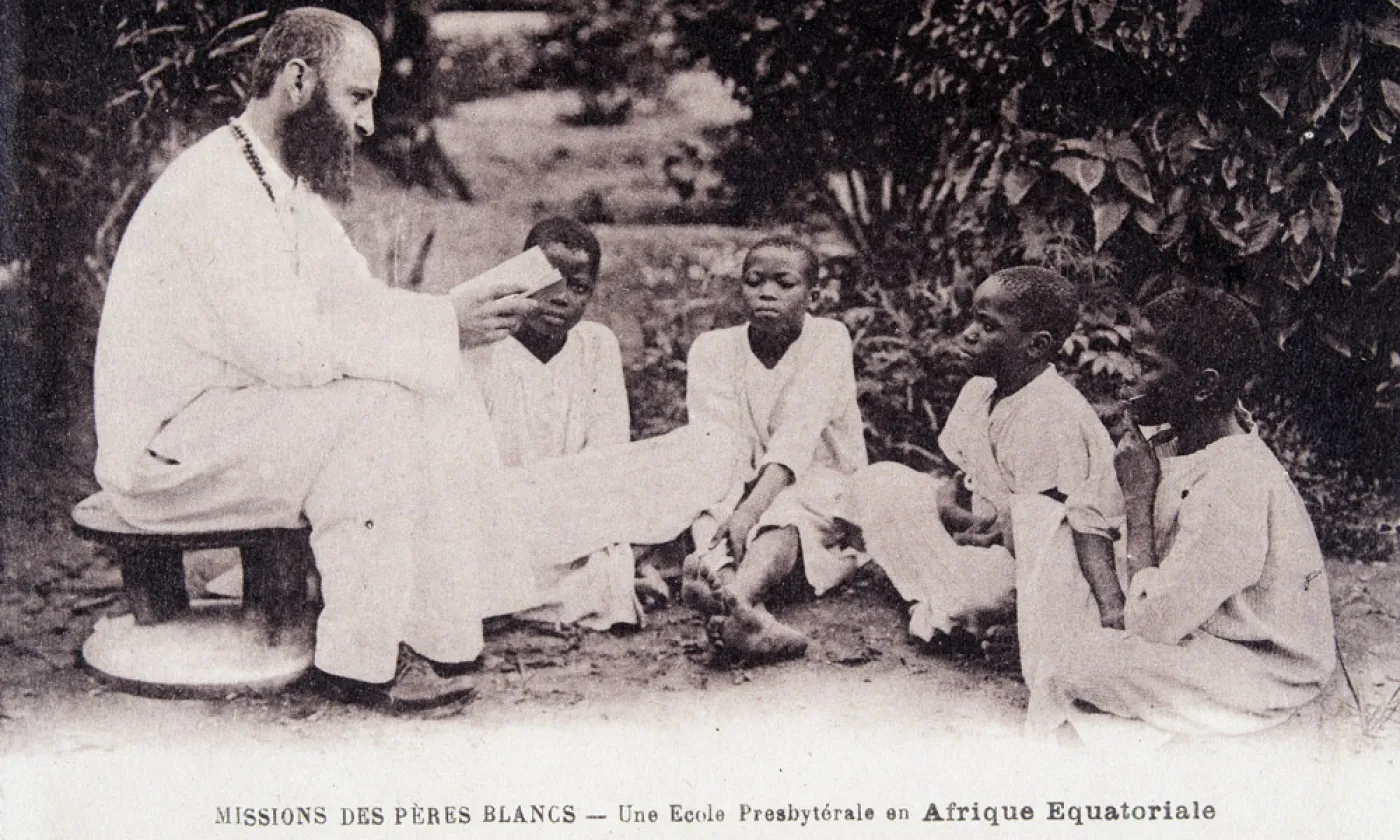 Missionnaire en Afrique : un membre de la société missionnaire des Pères Blancs enseignant à des enfants dans une école d'Afrique équatoriale. Carte postale des années 1930 ©Collection Sirot-Angel/leemage © Wikimedia Commons